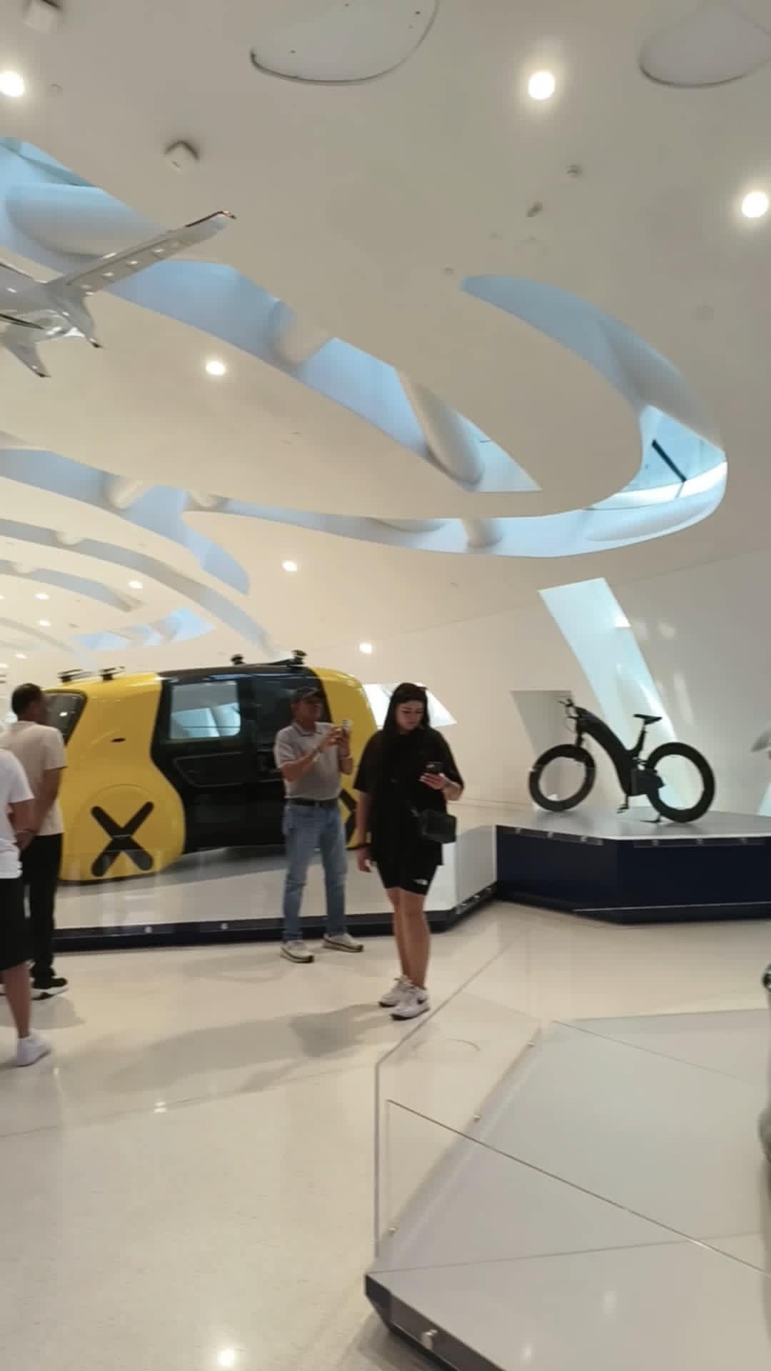 Futuristic electric cars on display at the Museum of the Future Dubai, with visitors observing advanced automotive technology and design.