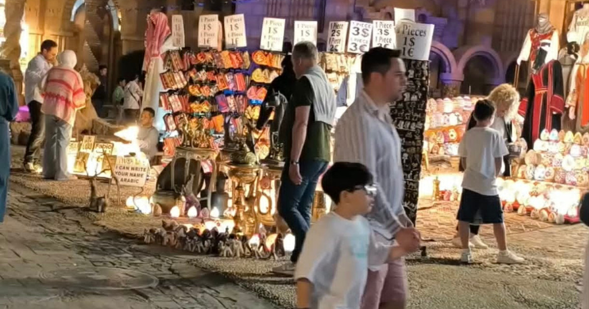 Tourists browsing traditional souvenir stalls and local handicrafts in the illuminated Old Market of Sharm El Sheikh.